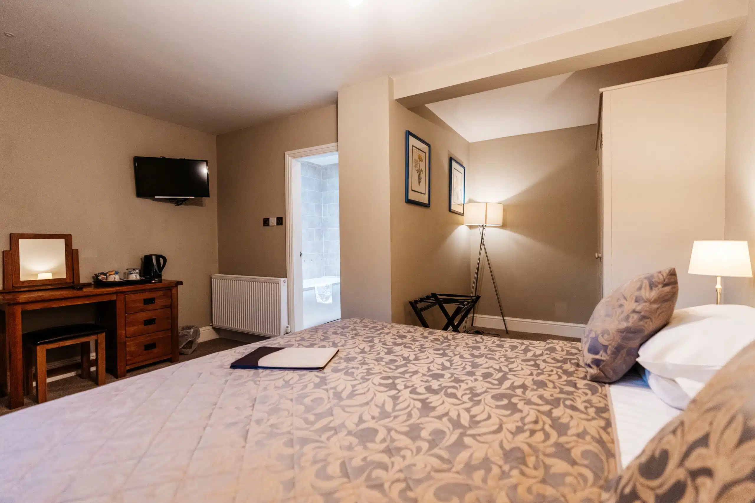 A double room with a patterned bedspread and bedside lamp